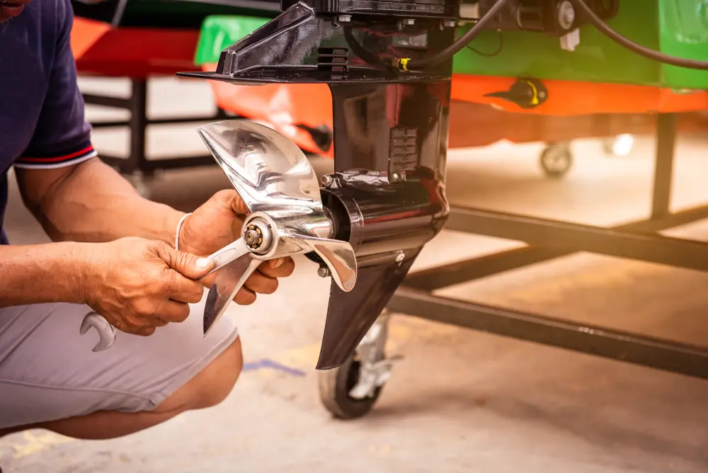 Technician handling the lower unit and propeller of an outboard motor