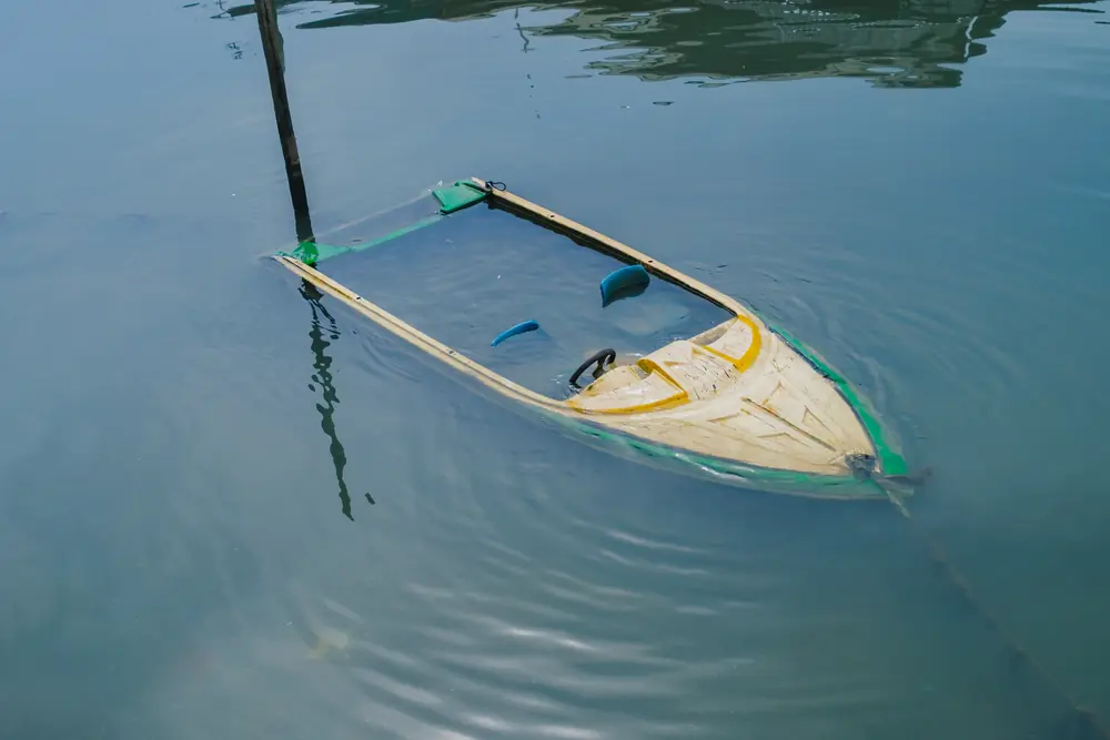 Small boat partially submerged in still green water